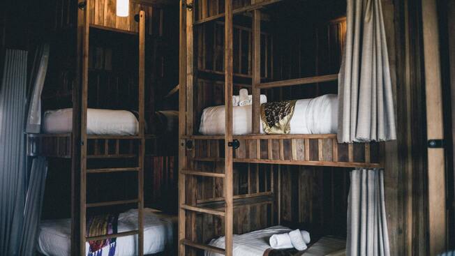 Une chambre avec plusieurs lits superposés en bois disposant de rideaux