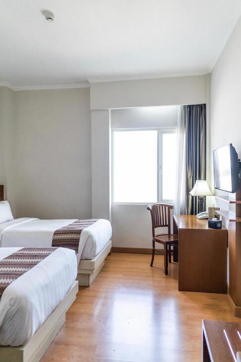 Une chambre avec deux lits doubles, une fenêtre et un bureau