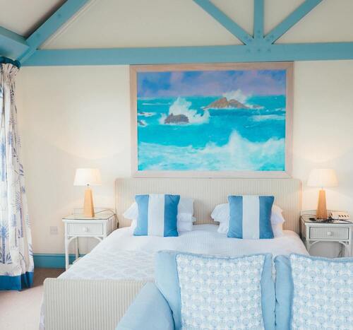 Une chambre à dominante bleue turquoise avec un lit double et un tableau de la mer au dessus du lit