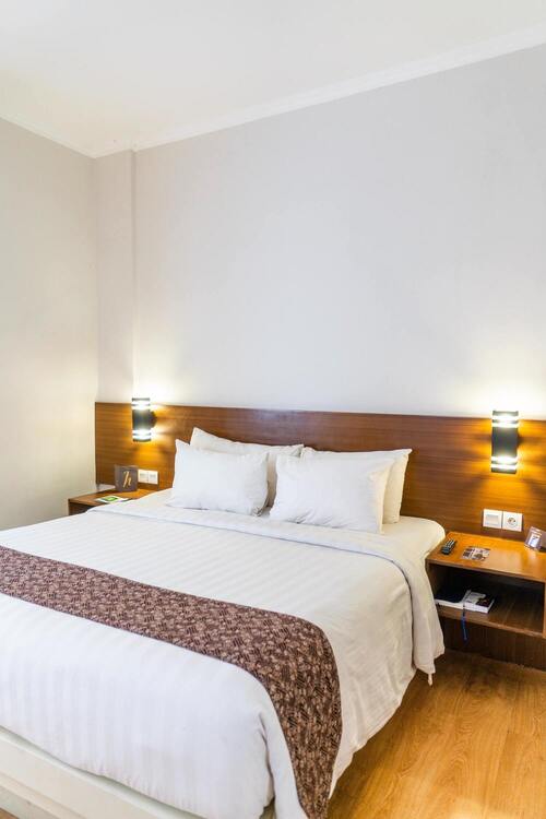 Une chambre parquetée avec un lit double et des tables de nuit